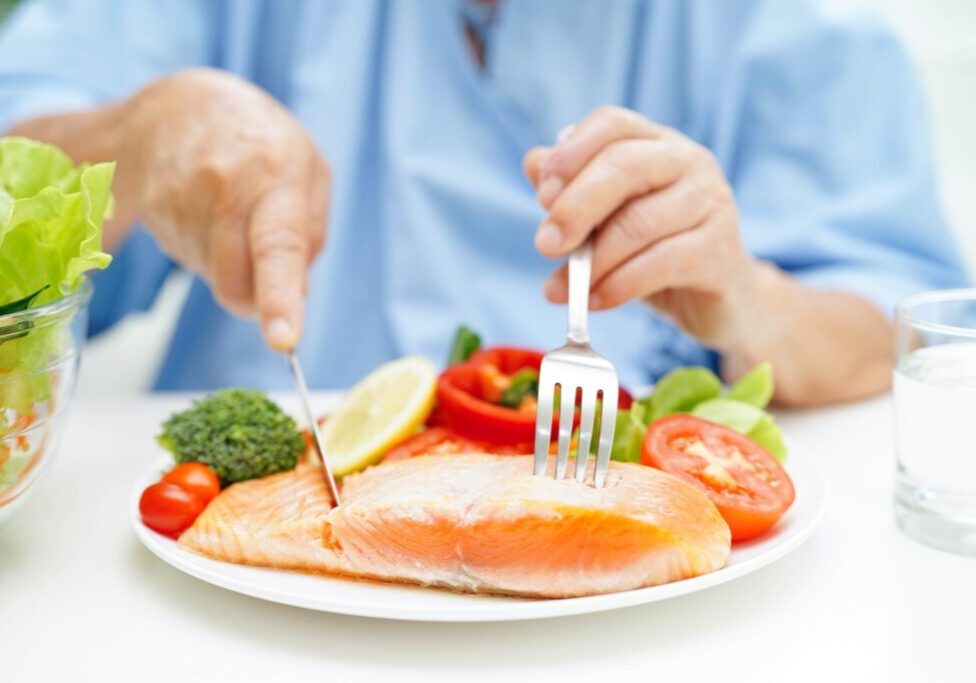 Asian,Elderly,Woman,Patient,Eating,Salmon,Stake,And,Vegetable,Salad